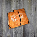 Both drawstring bag sizes on weathered wood boards