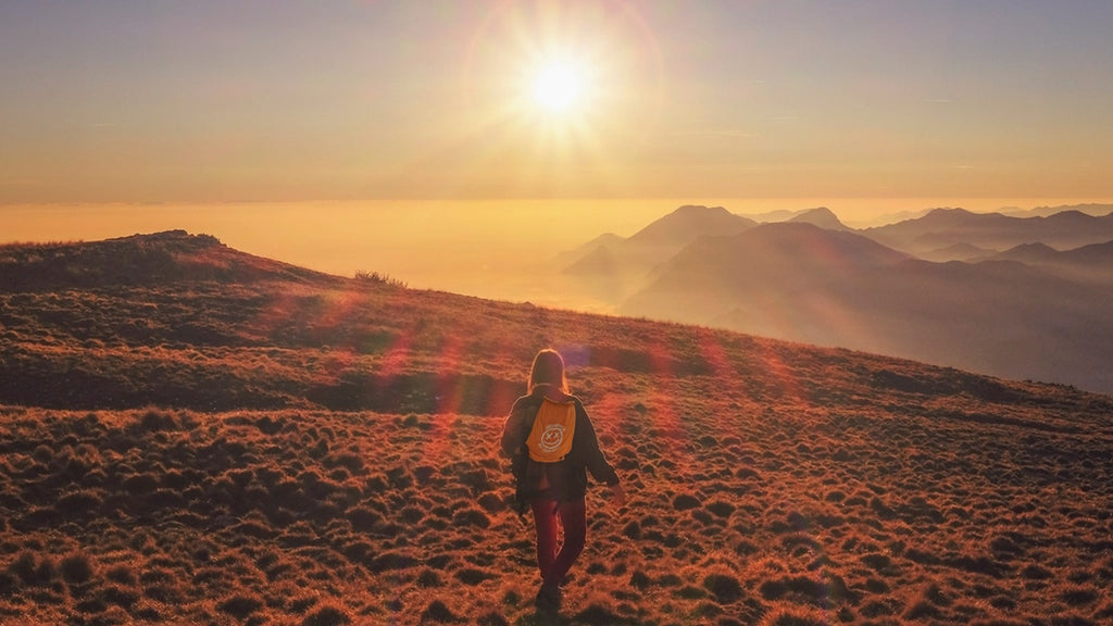 Hiker wearing Safe's Not Fun drawstring bag walking into mountain sunrise